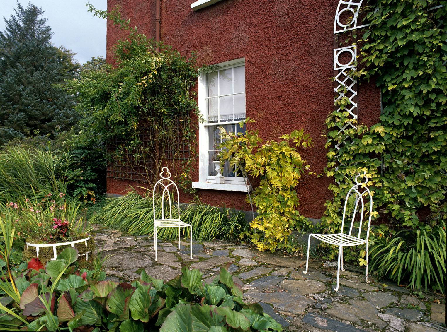 The south-facing terrace with iron chairs made by the local blacksmith to Derek Hill's design. OPW. 